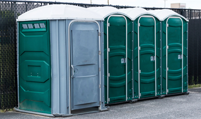 handicap accessible porta potty in a fenced parking lot